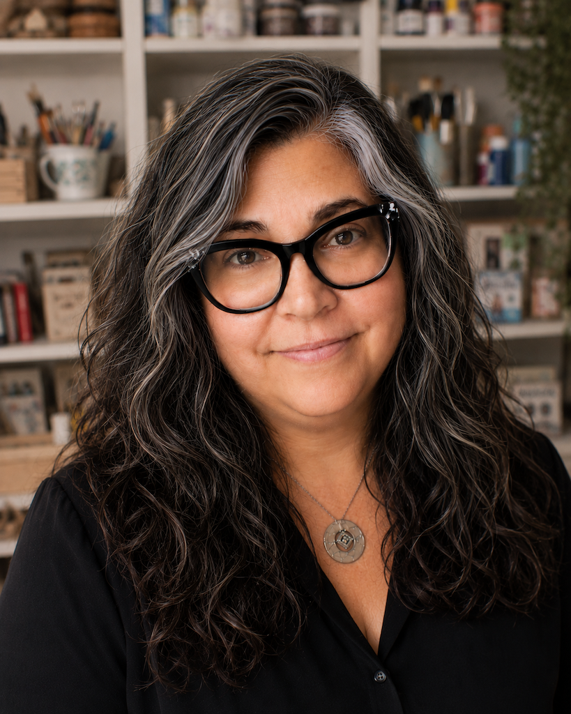 Wendy Solganik smiling in her studio, in front of shelves filled with art supplies
